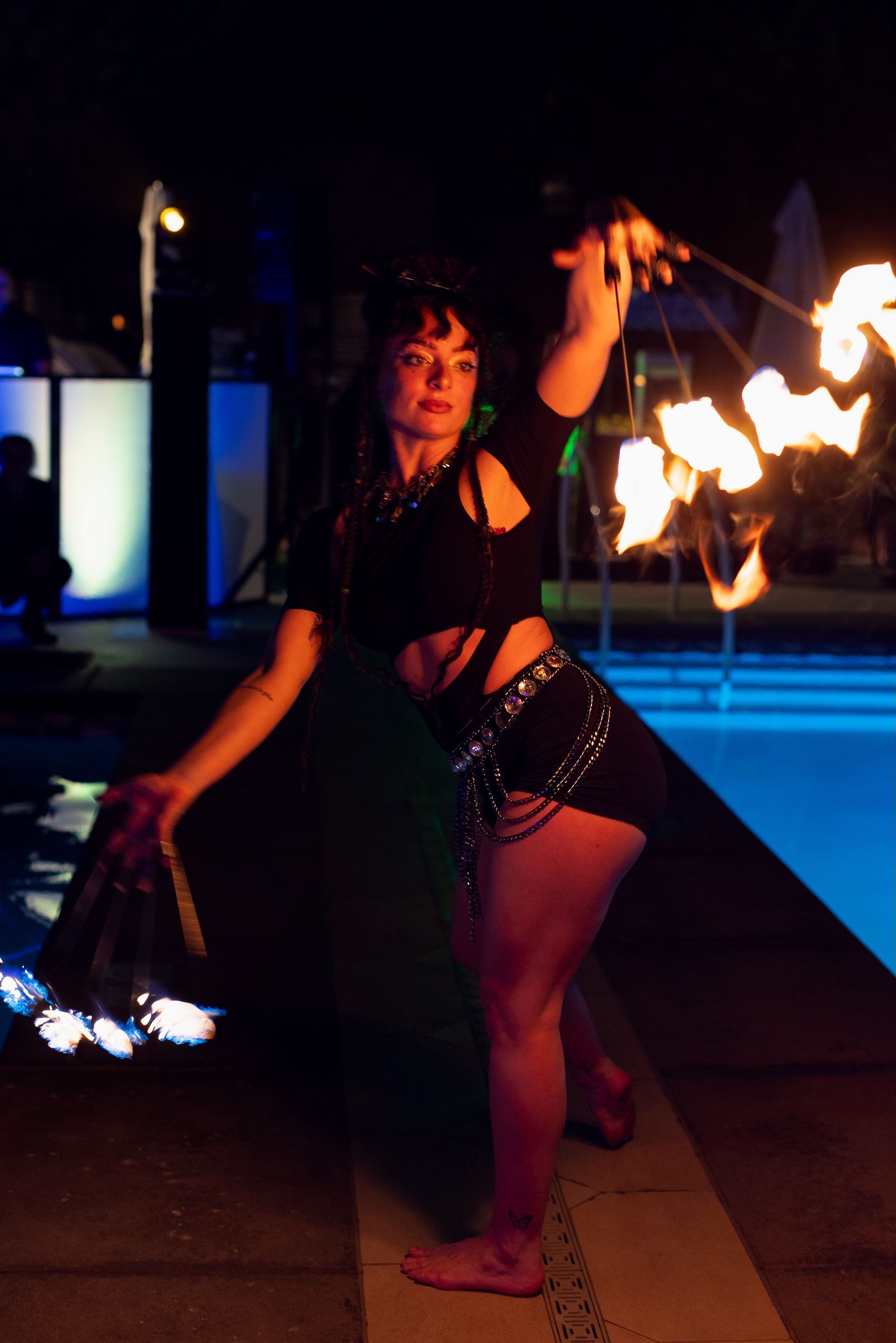 A woman is holding a torch in front of a pool at night