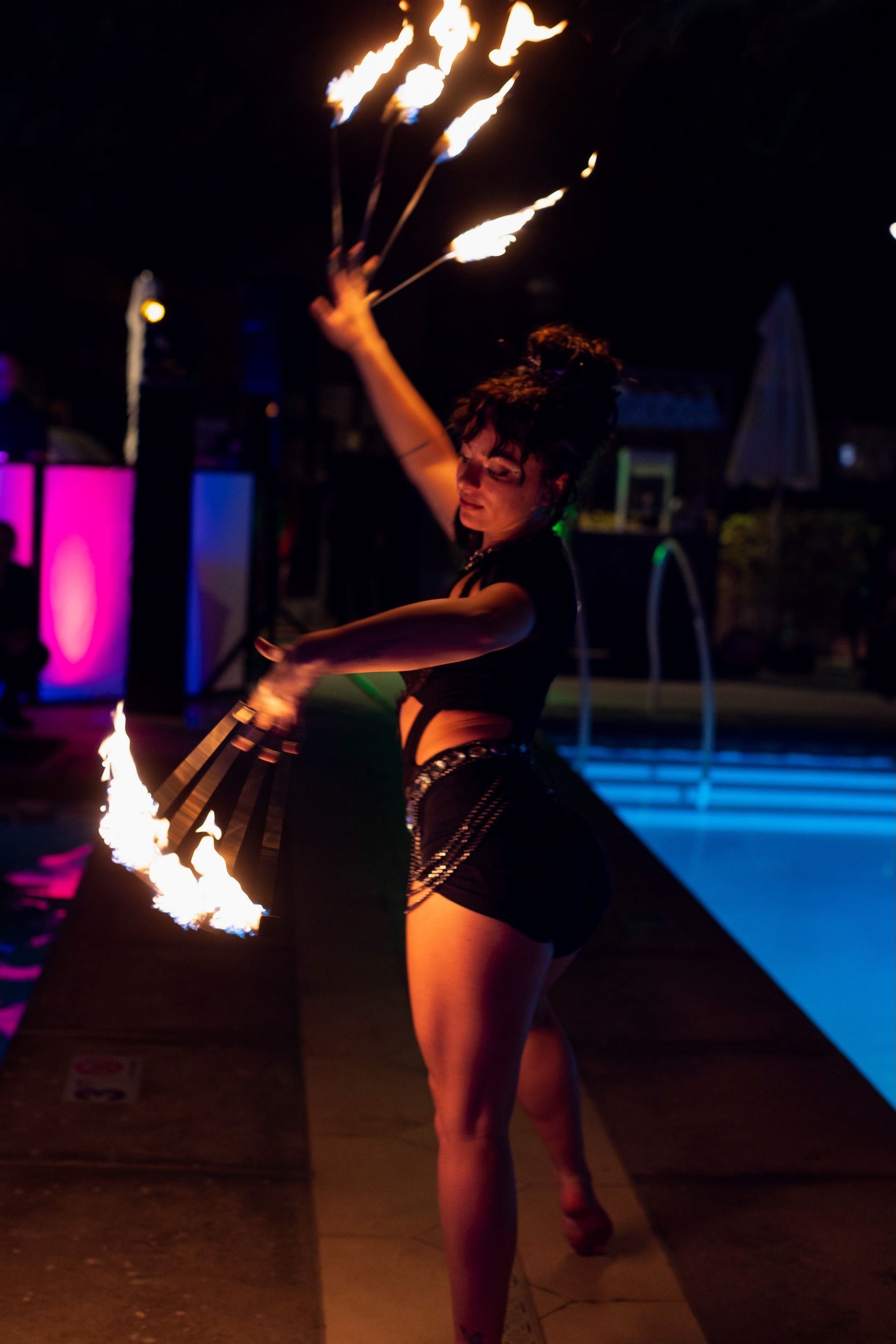 A woman is holding a bunch of fire sticks in front of a pool