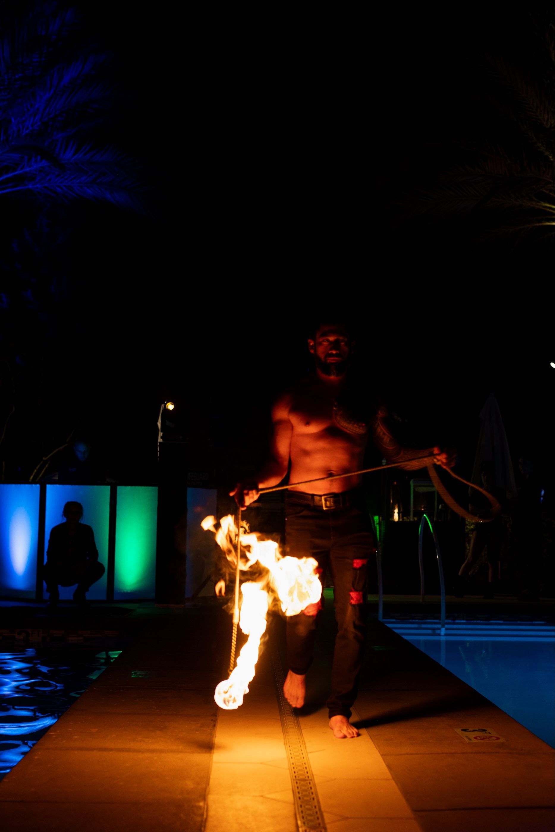 A man is walking down a sidewalk with a torch in his hand.