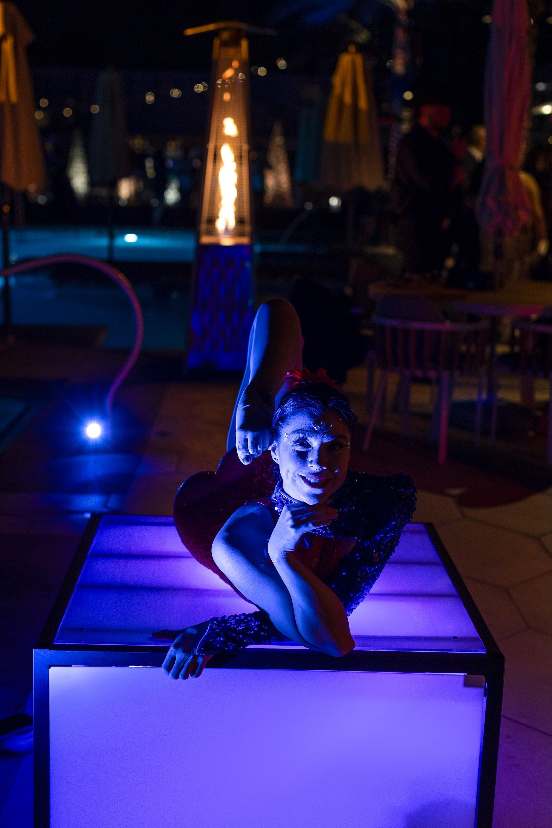 A woman is doing a trick in a box at night.