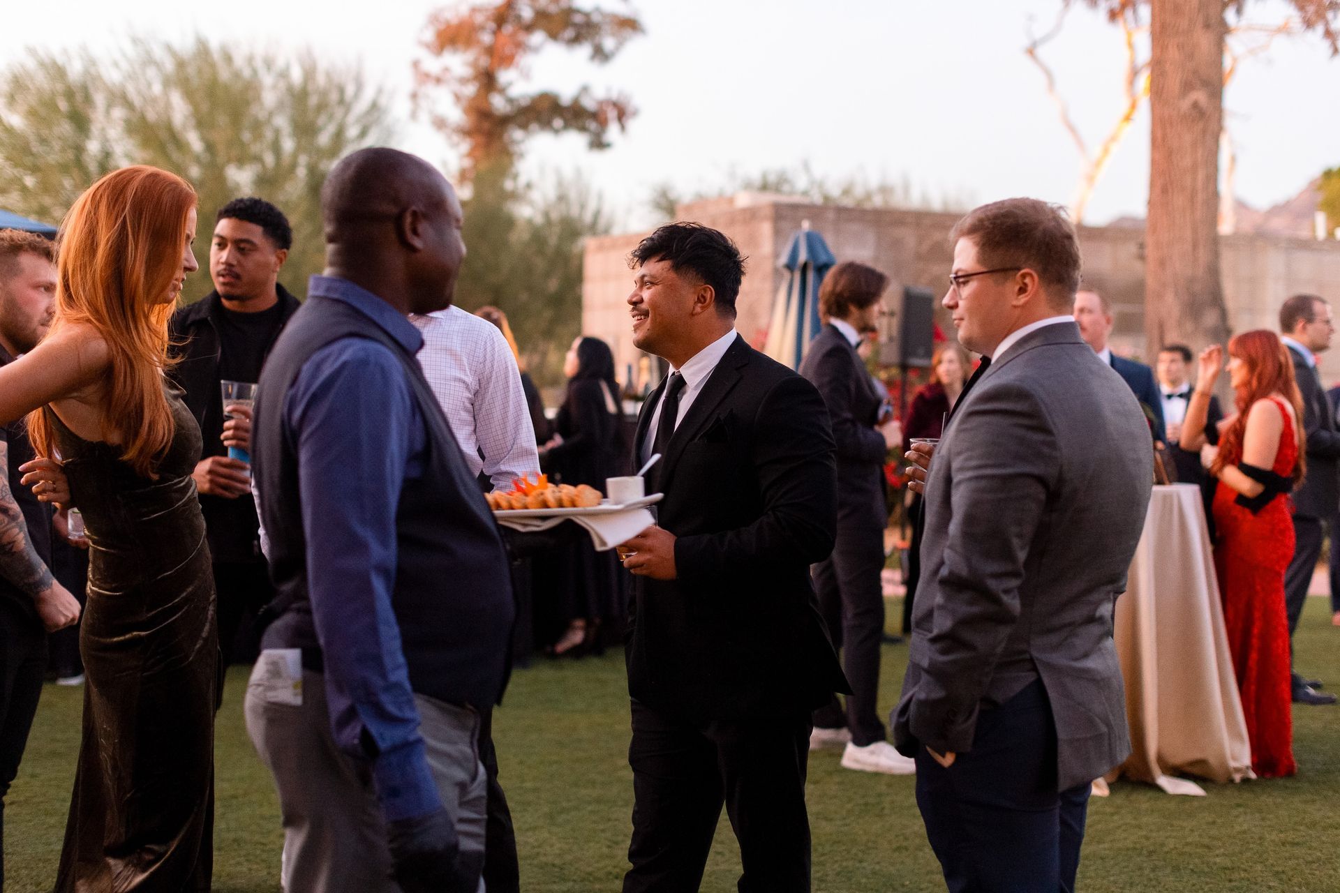 A group of people are standing in a field talking to each other.