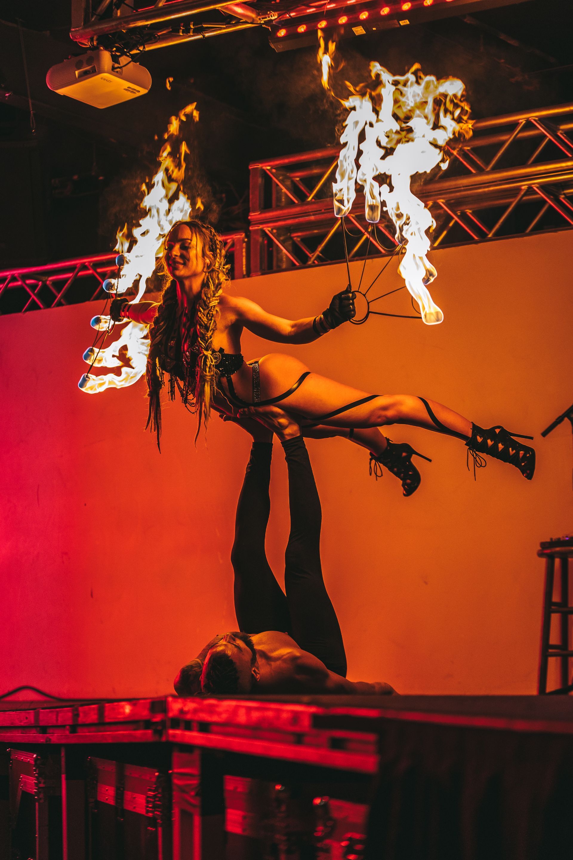A woman is being lifted in the air by a man while holding a fire torch.