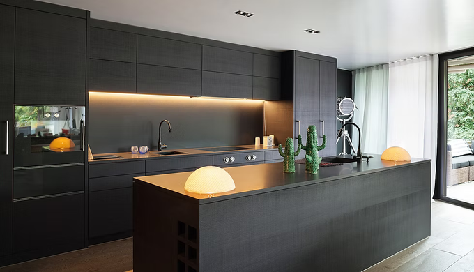 A modern kitchen with black cabinets and a large island.