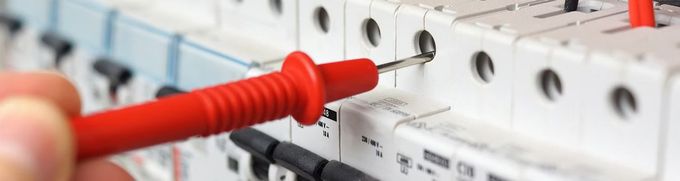 A person is using a multimeter to test a circuit board.