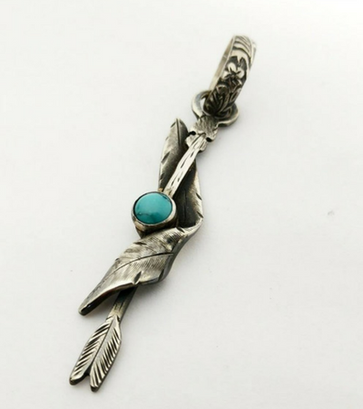A silver pendant with a feather and a turquoise stone