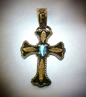 A gold cross with feathers and a blue stone