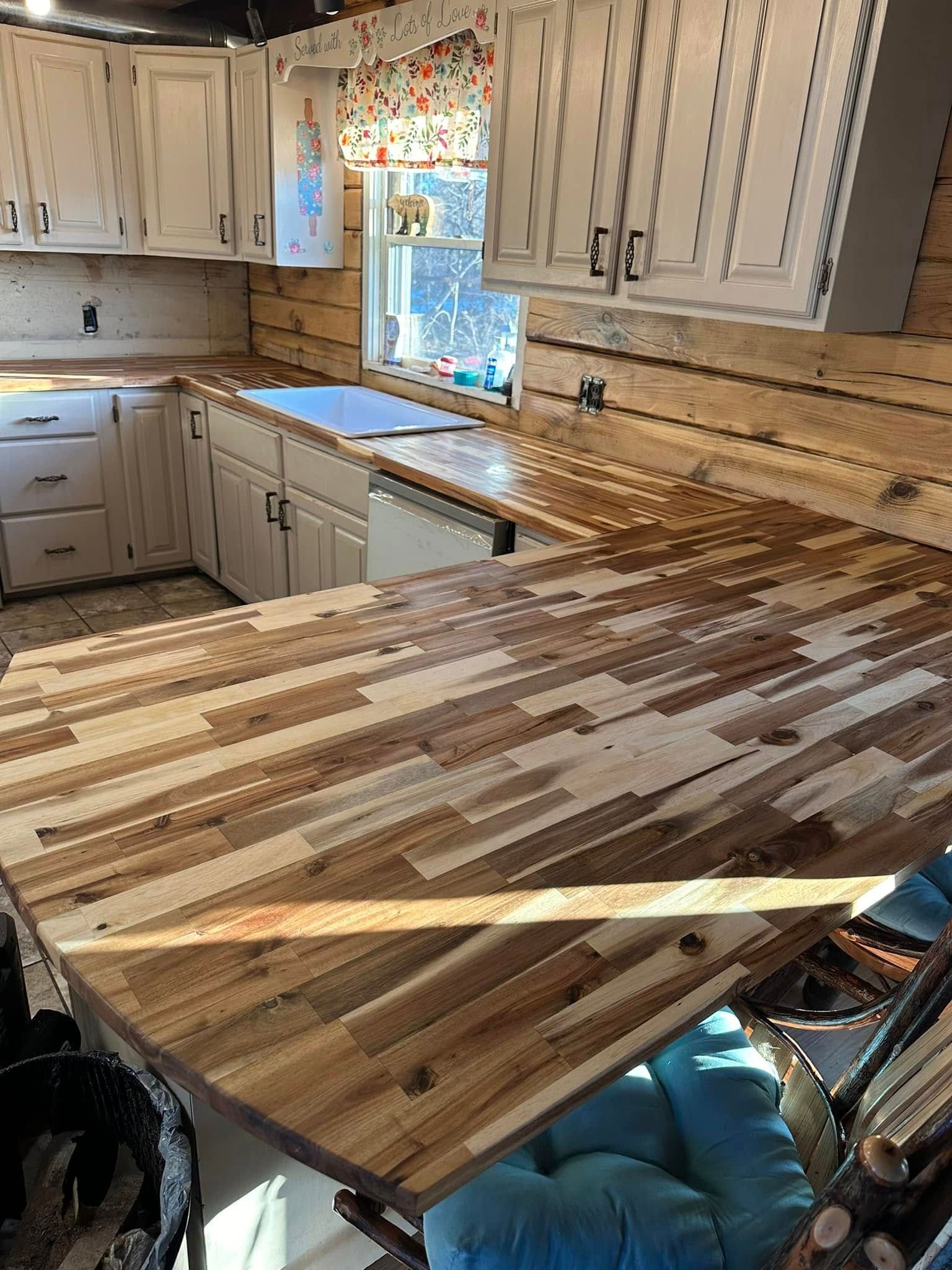 Kitchen with white cabinets, wood countertops, and a window with colorful floral curtains.