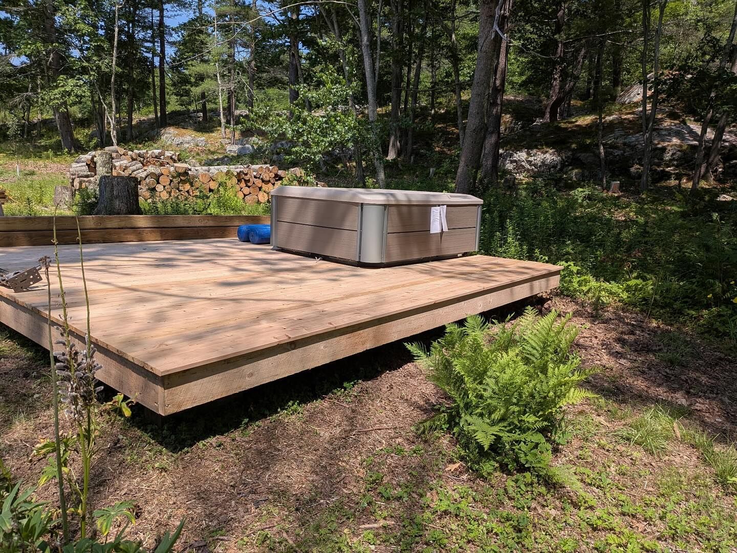 Hot tub on a wooden deck surrounded by trees and greenery.
