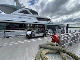 A golf cart is parked in front of a large boat.