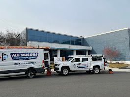 Two all seasons trucks are parked in front of a large building.
