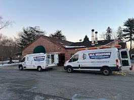 Two vans are parked in a parking lot in front of a building.