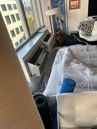 A room with a bed , a guitar , a lamp and a window.