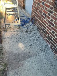 A brick wall with a lot of dirt on it next to a ladder.