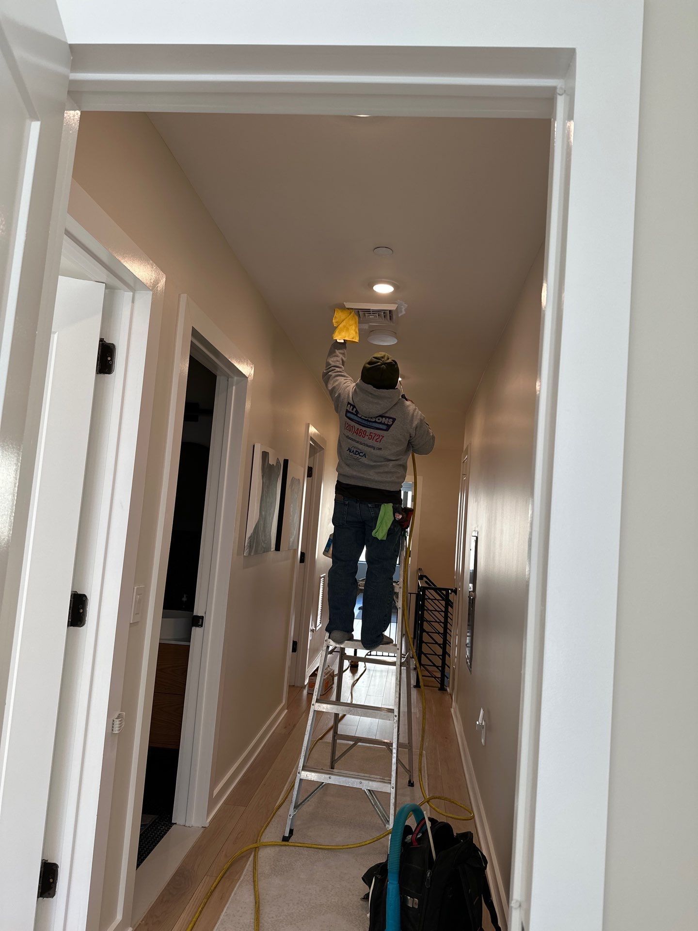 A man is standing on a ladder in a hallway.