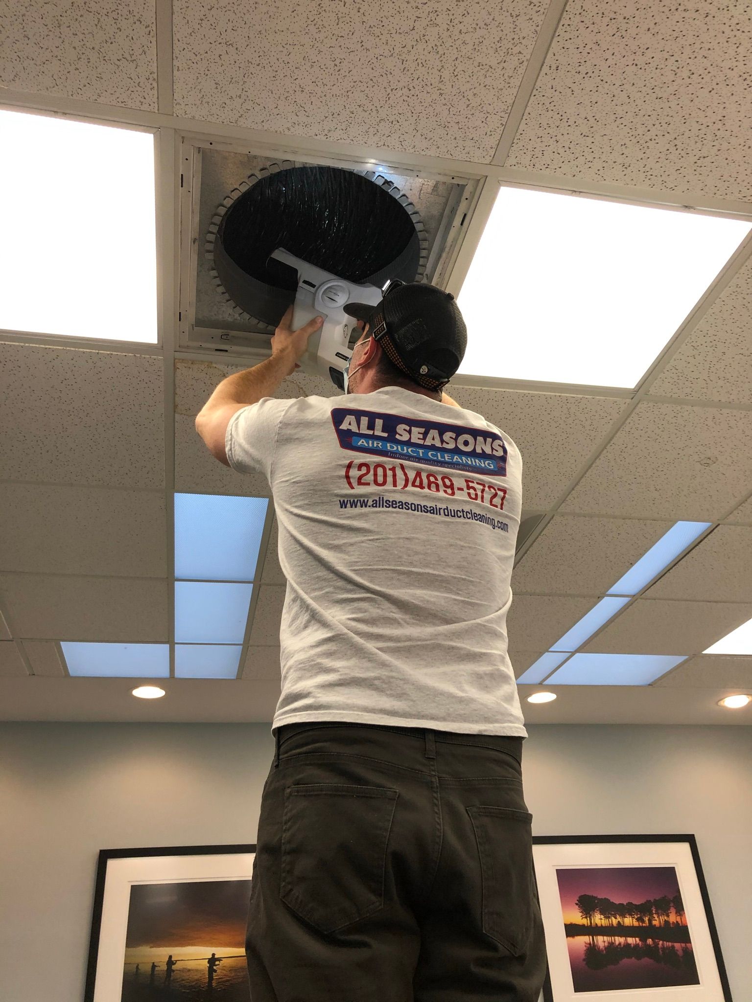 A man in a white shirt is working on a ceiling fan.