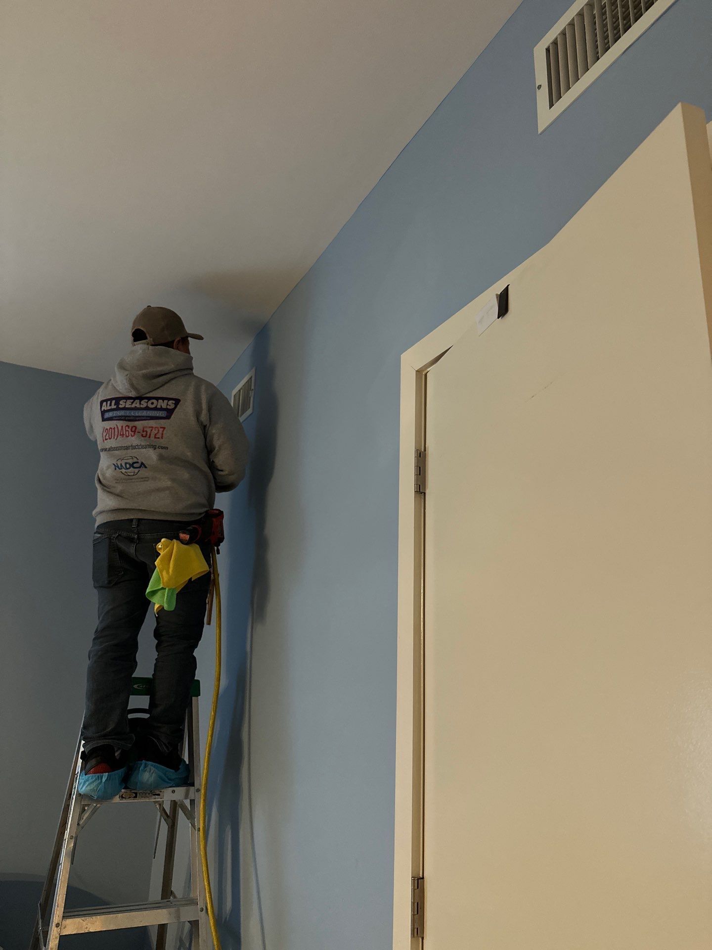 A man is standing on a ladder painting a wall.