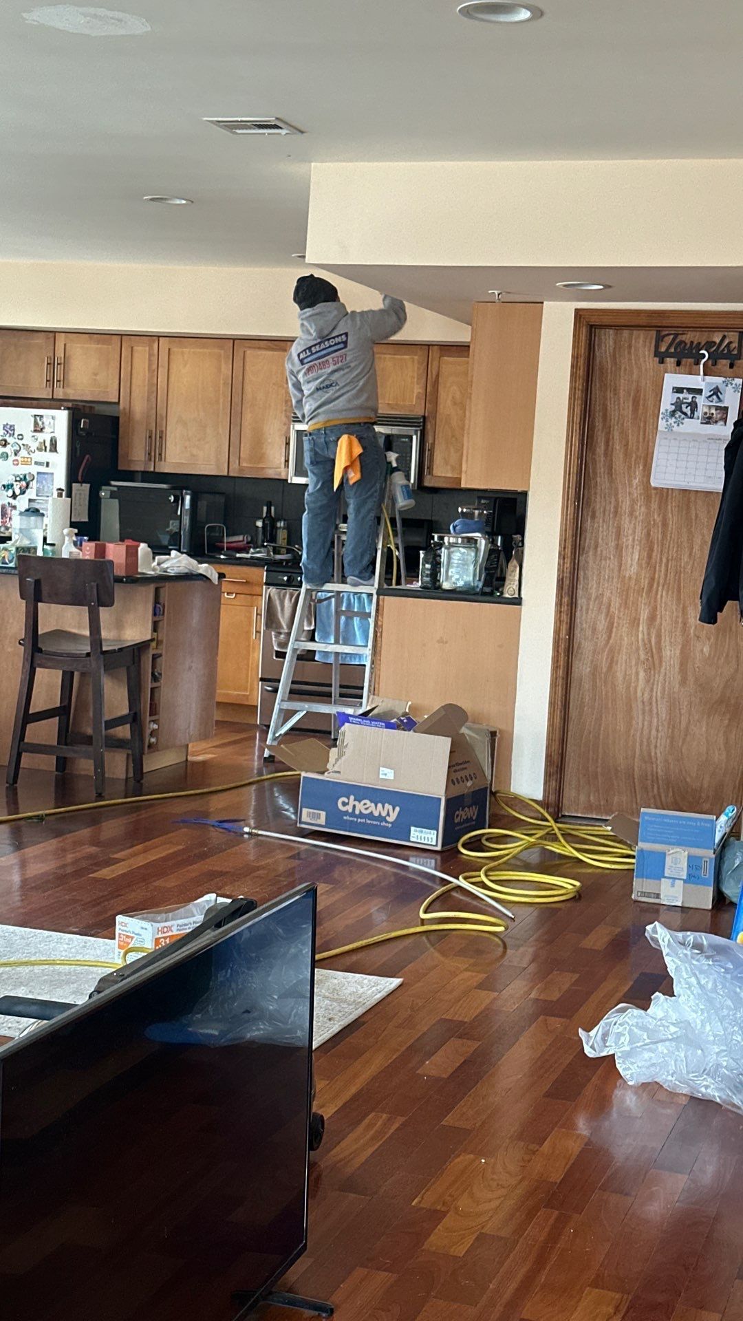 A man is standing on a ladder in a kitchen.