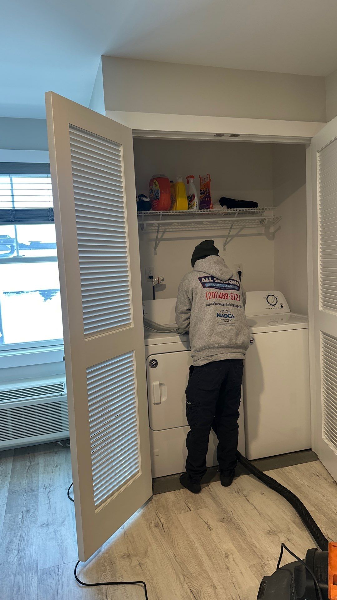 A man is standing in a laundry room next to a washer and dryer.