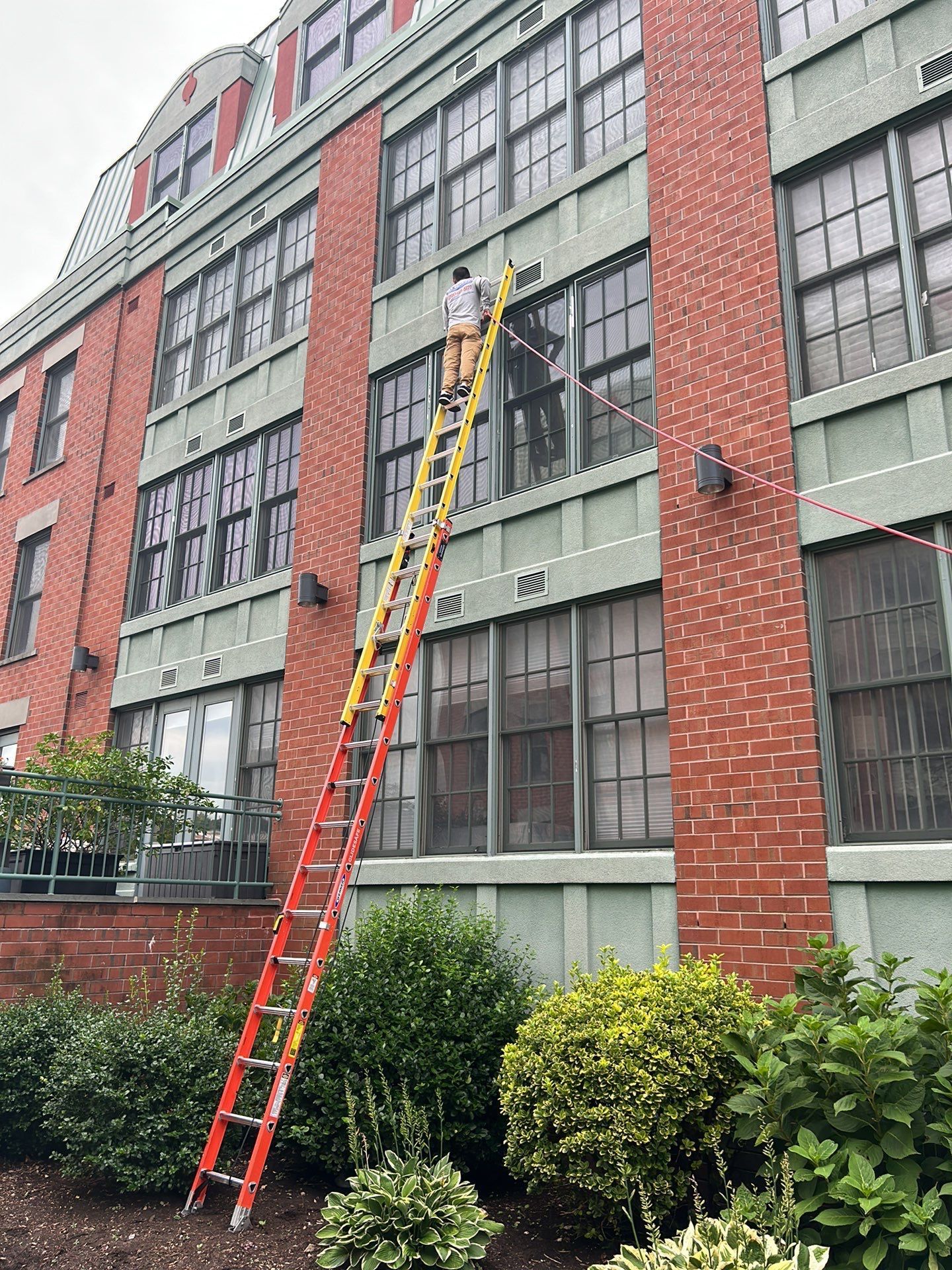 A man is standing on a ladder on the side of a building.