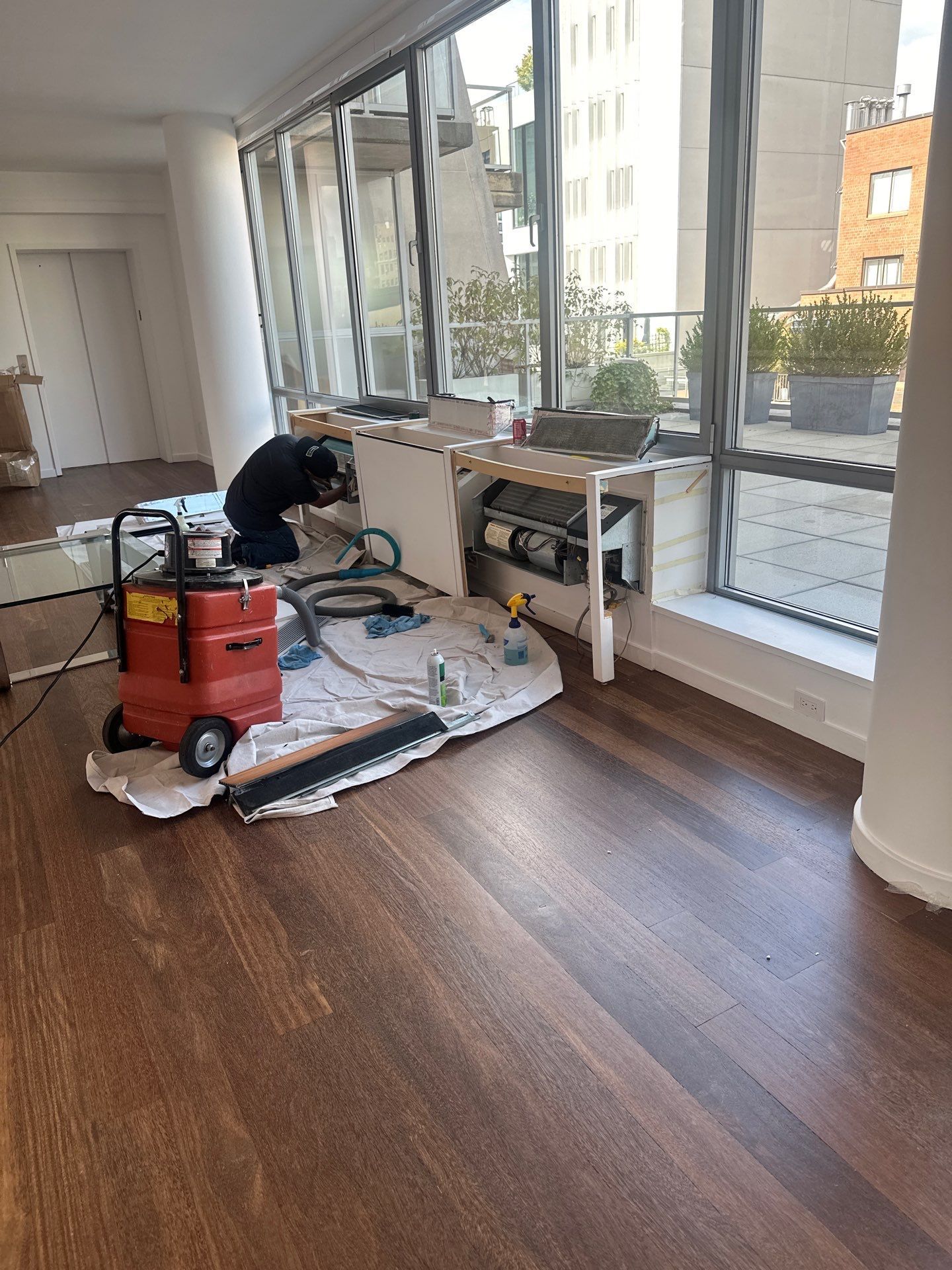 A man is working on a wooden floor in a living room.