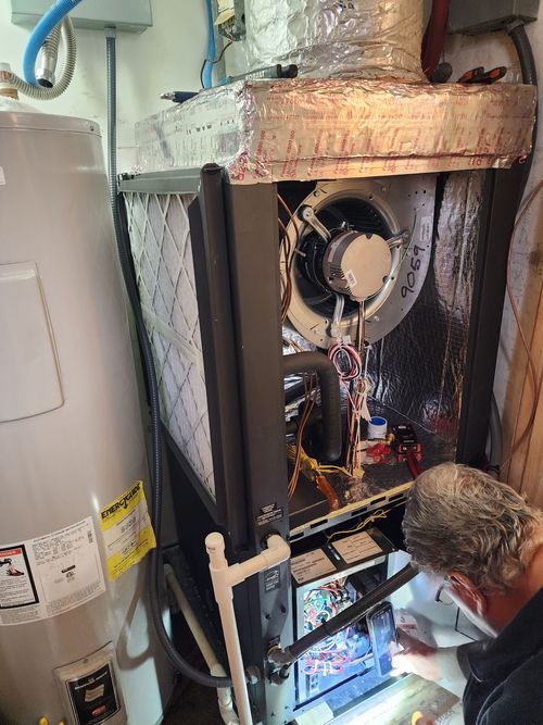 A man is working on a water heater in a room.