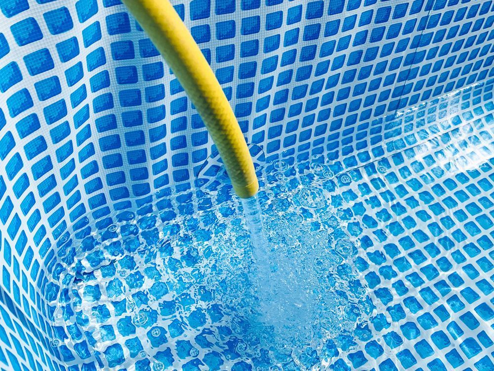 A Yellow Hose Filling Blue and White Patterned Inflatable Pool With Water — Cascade Pool & Spa Centre in Port Macquarie, NSW