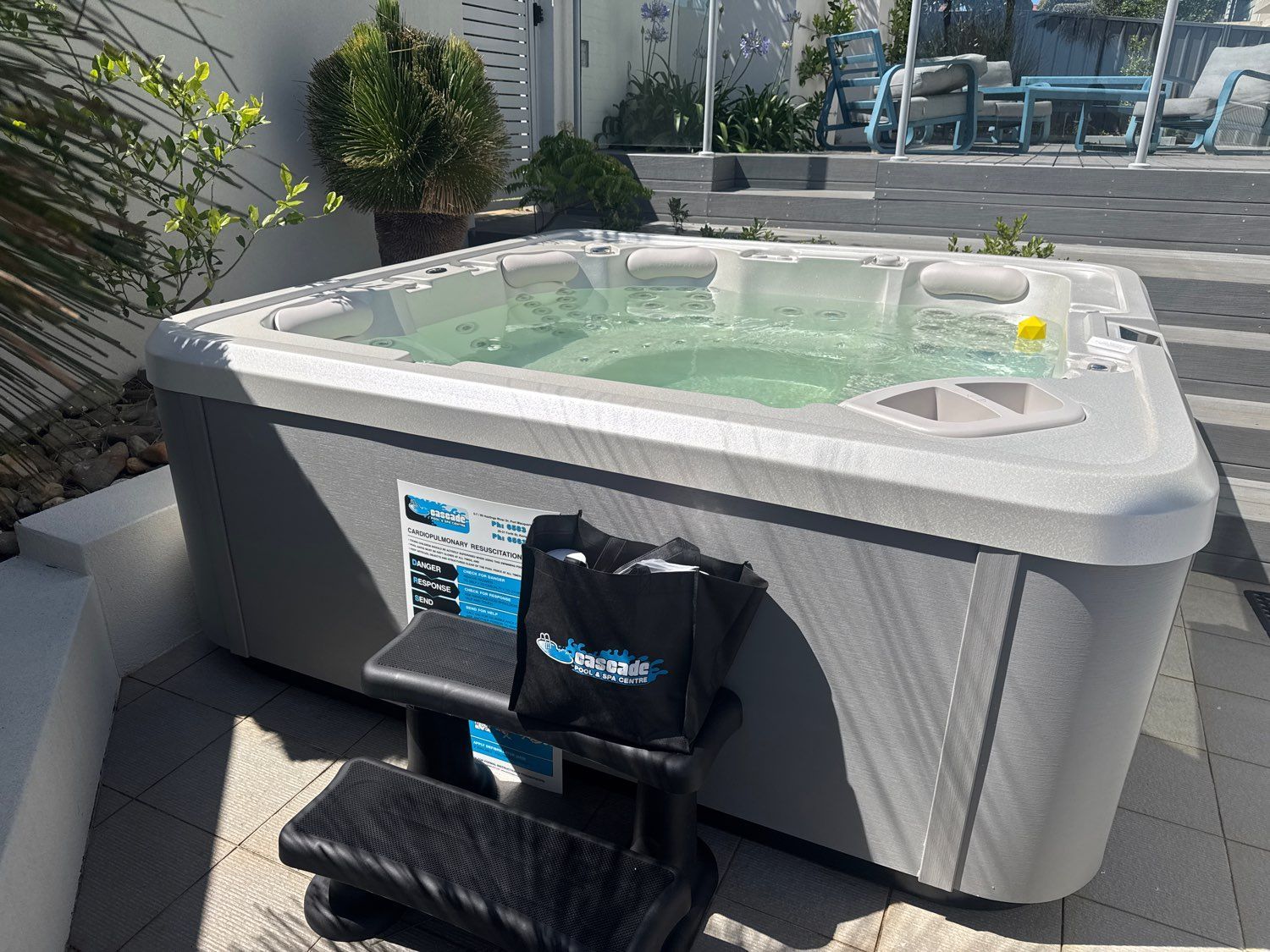Outdoor hot tub with clear water and floating ball on a patio, with a small step stool in front — Cascade Pool & Spa Centre in Port Macquarie, NSW