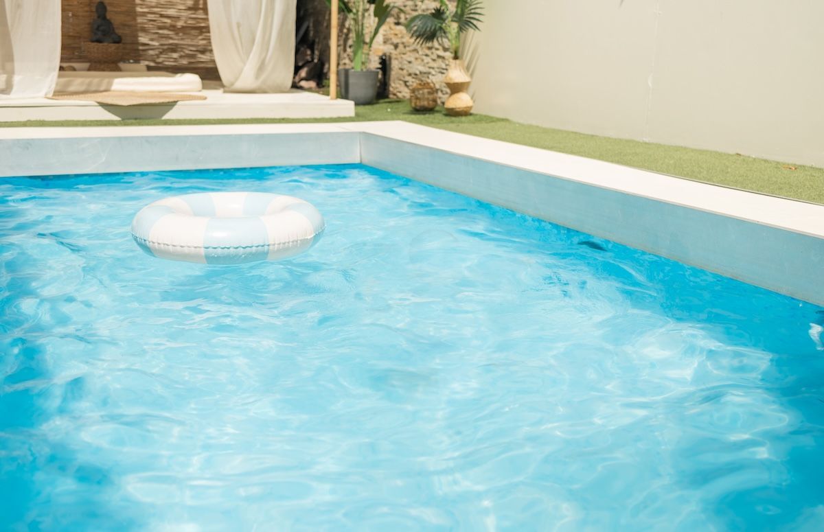 Swimming pool with a white inflatable ring floating on the blue water 