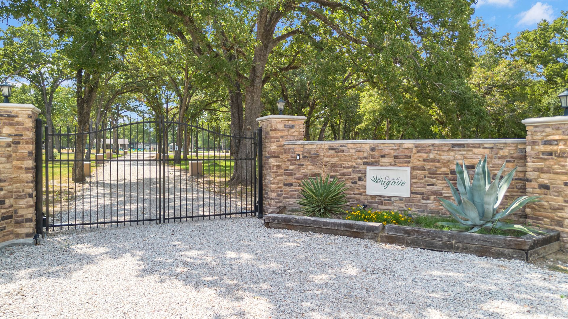 Black tiny home with a covered porch and large windows, set in a gravel area.