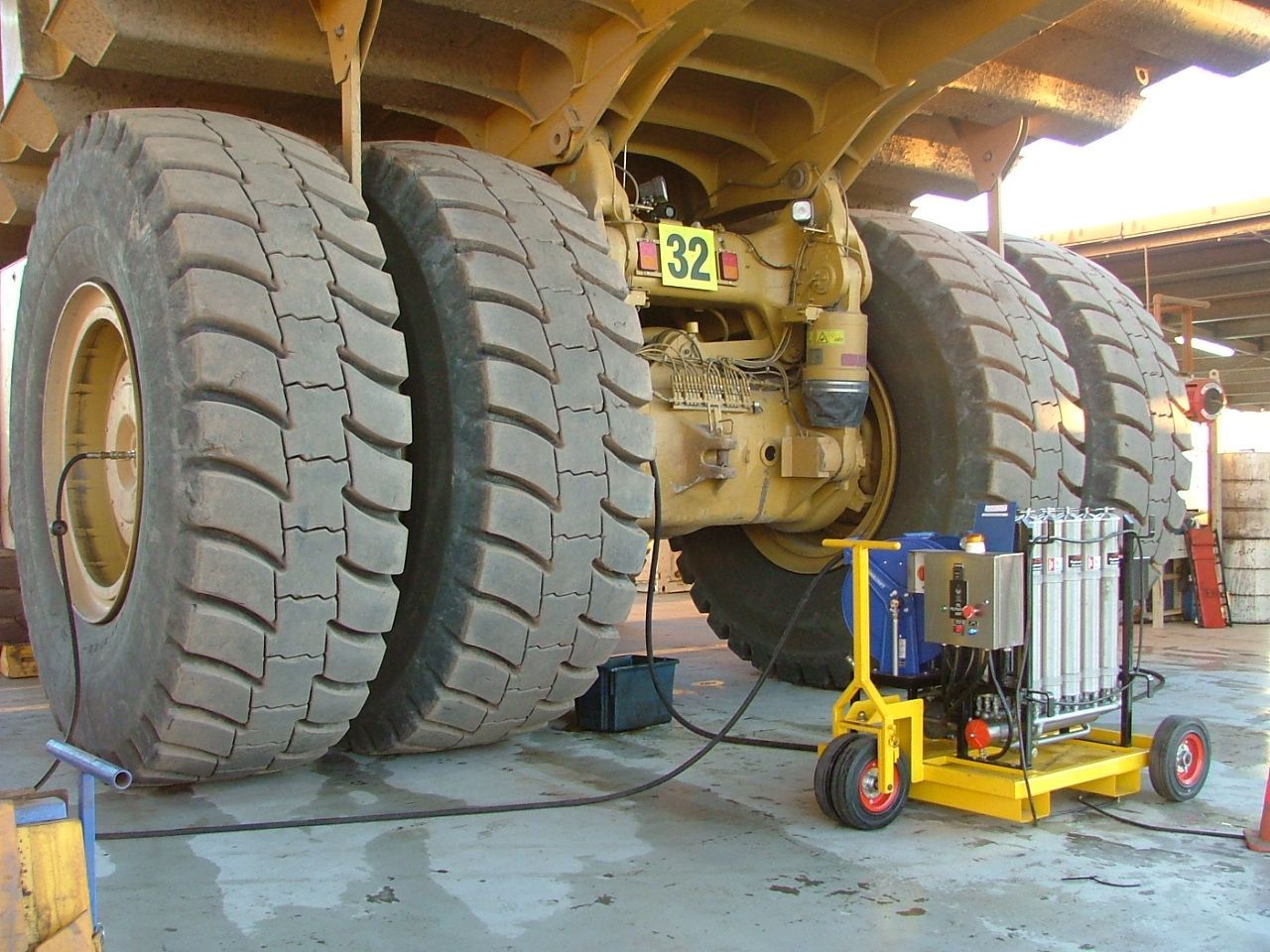 A large yellow machine is sitting under a roof in a parking lot.