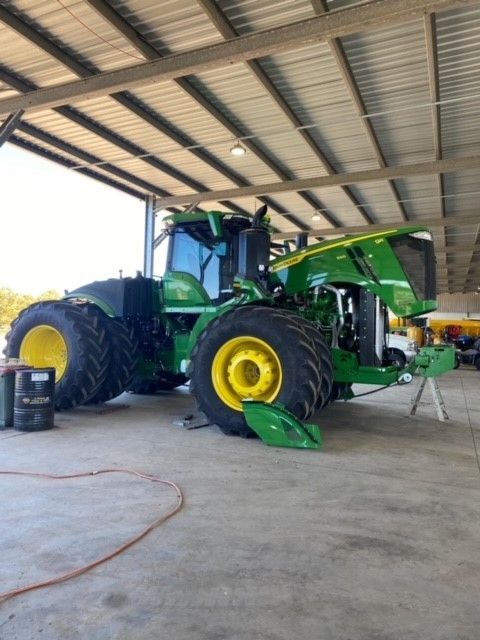 A green and yellow john deere tractor is parked in a garage