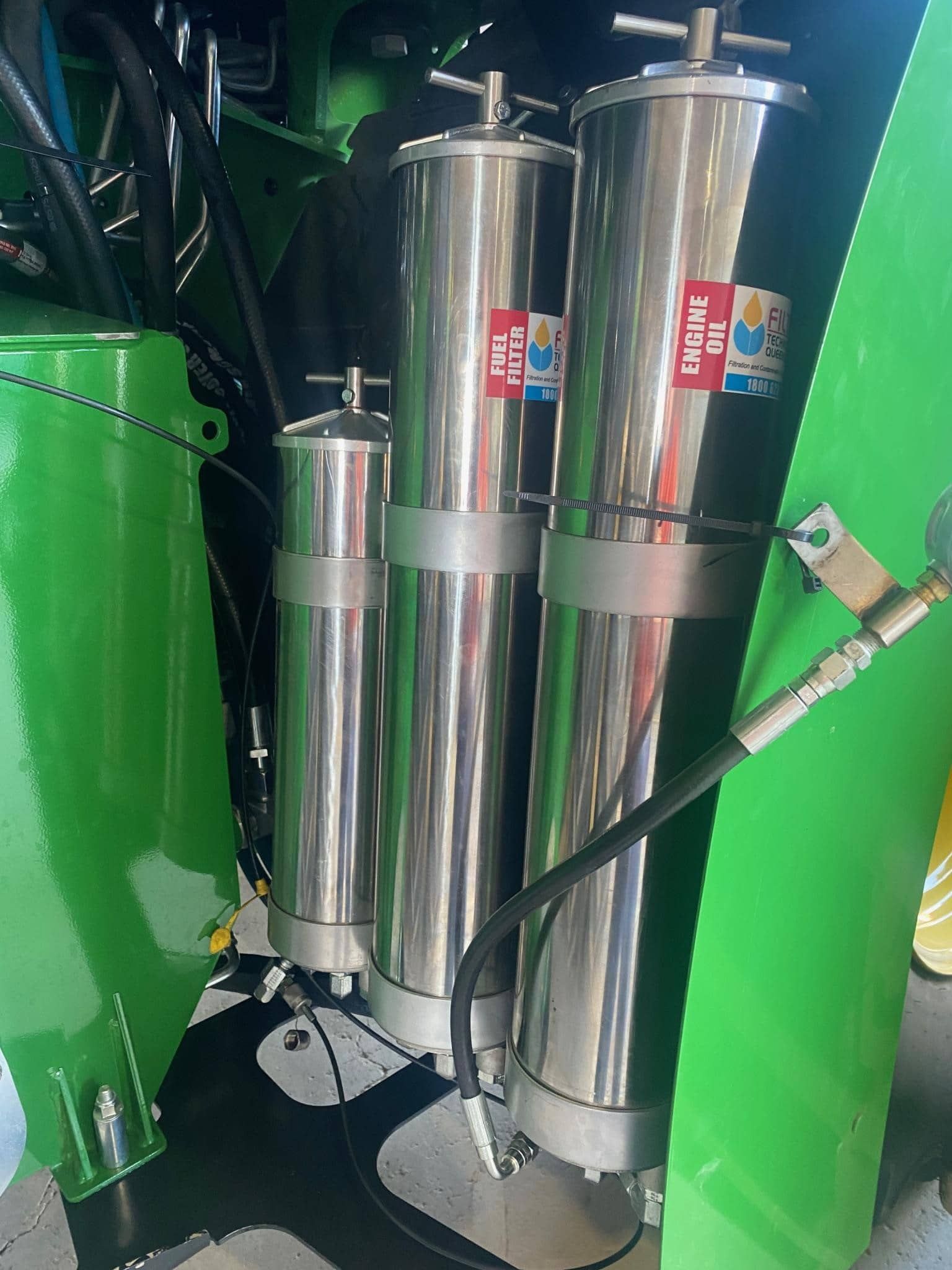 A green tractor with three stainless steel cylinders attached to it.