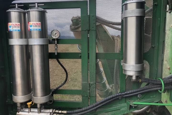 There are two stainless steel tanks on the side of a green tractor.