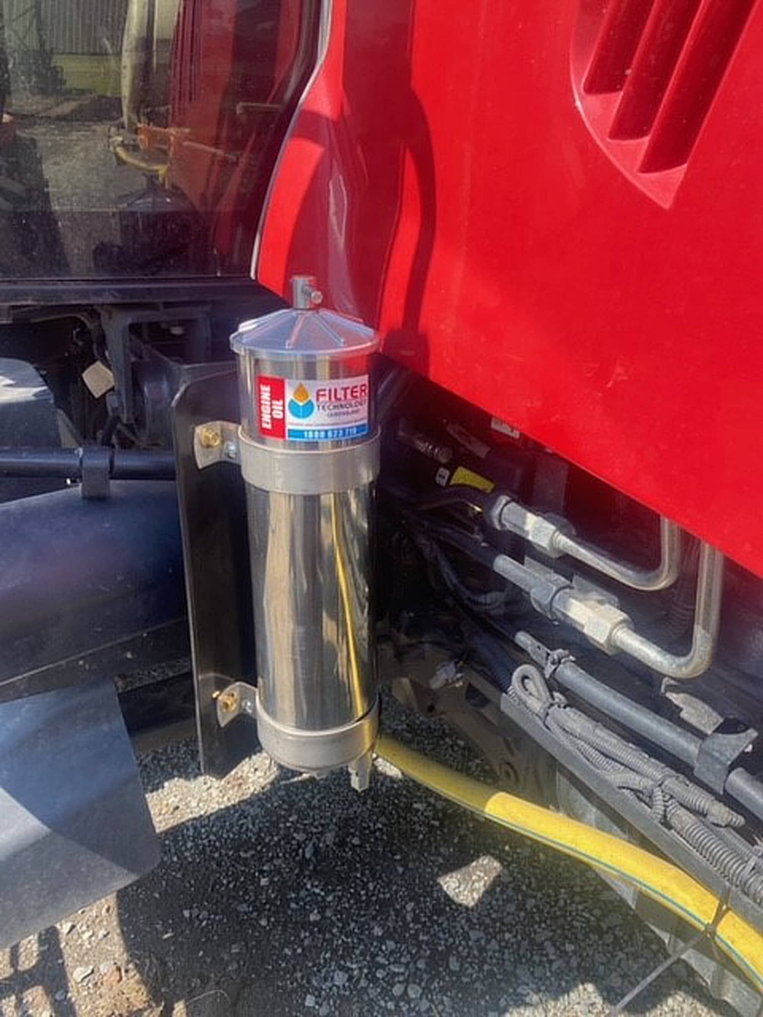 A stainless steel container is attached to the side of a red truck.