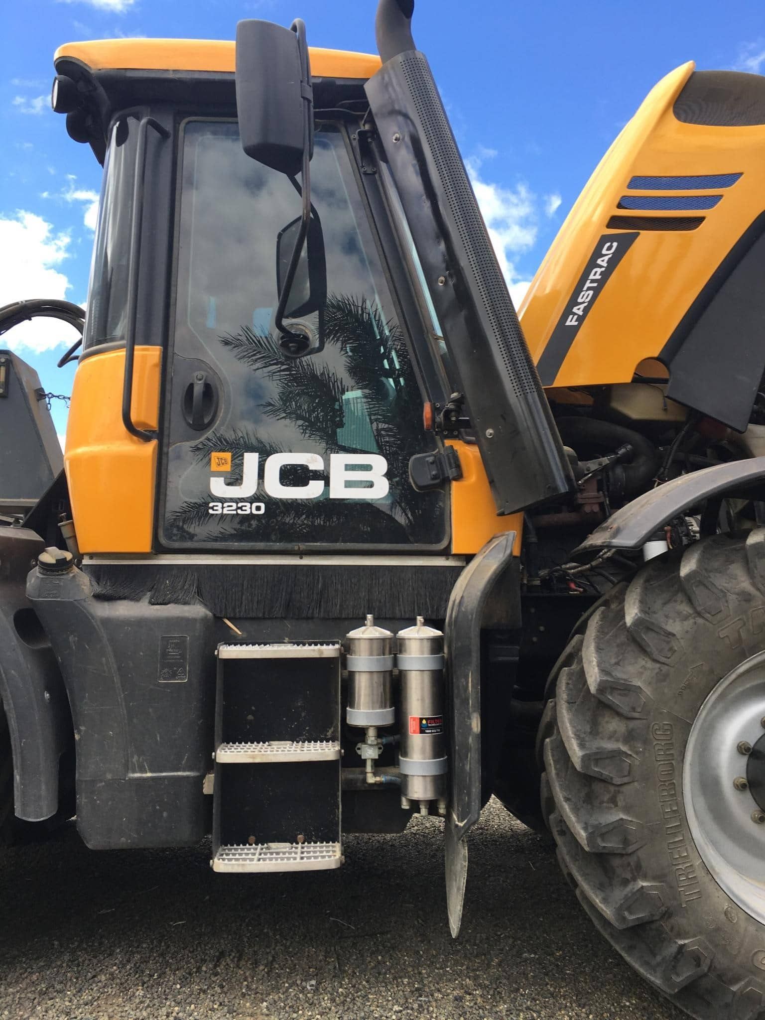 A yellow and black tractor is parked in a gravel lot.