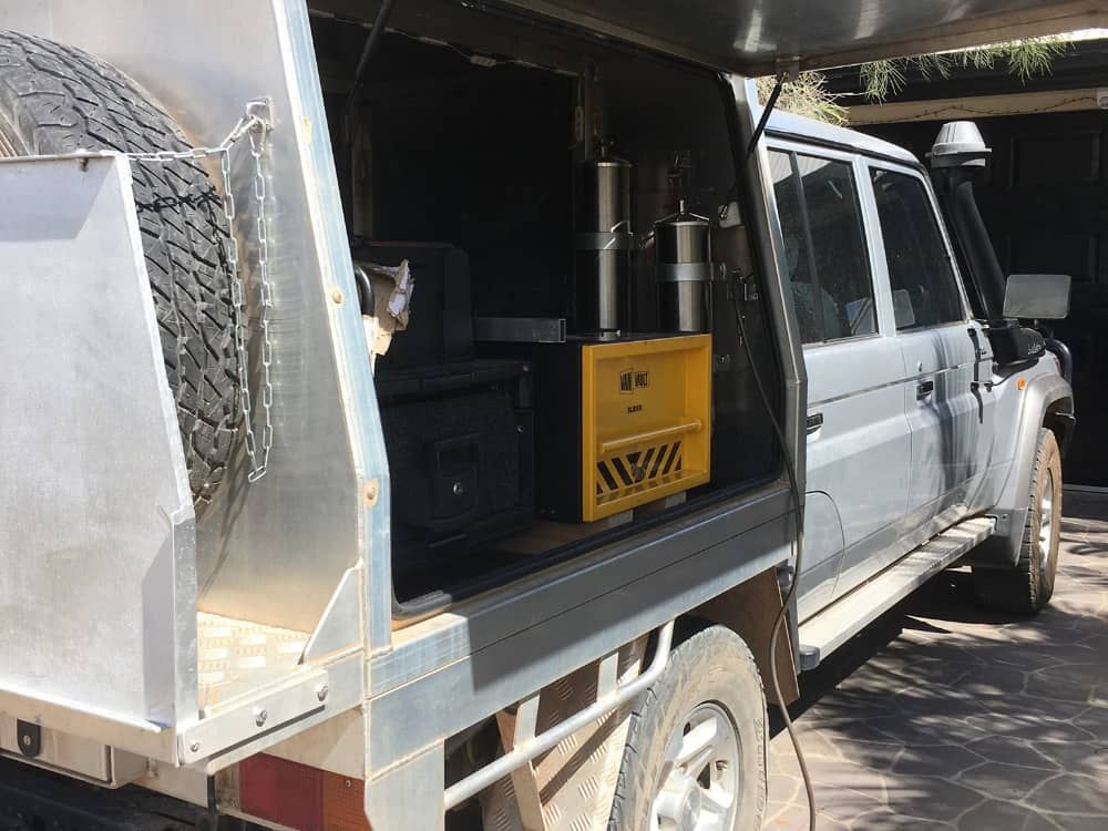 A silver truck with a canopy on top of it is parked in a driveway.