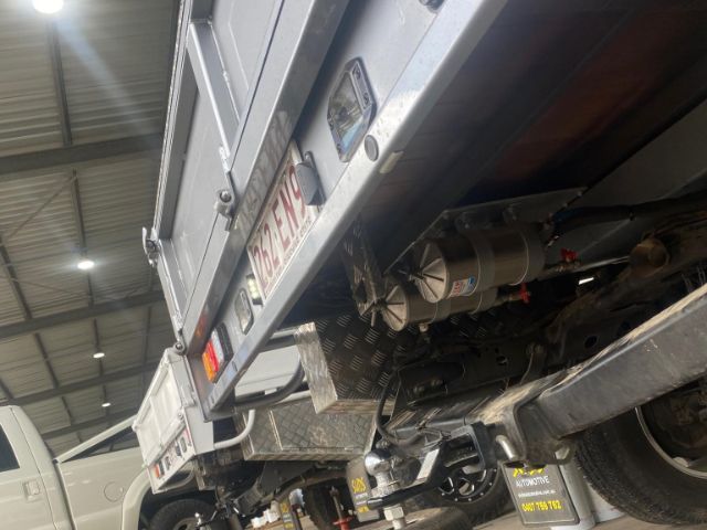 A truck is sitting on a lift in a garage with a license plate that says ' ec - 976 '