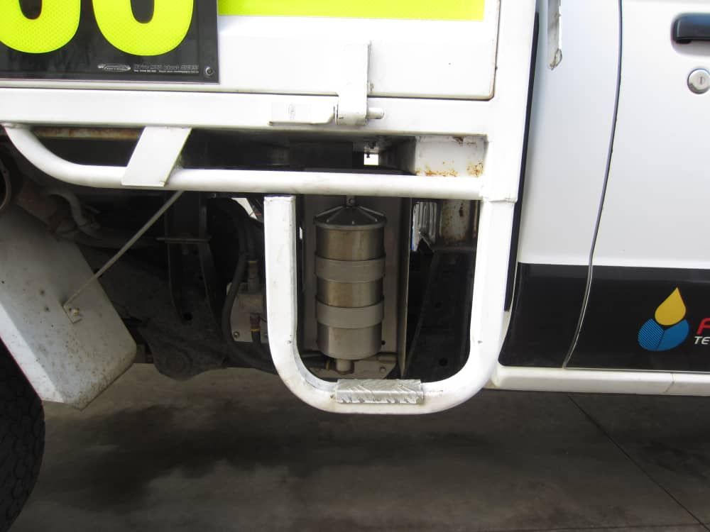 A semi truck is parked in a field with mountains in the background.