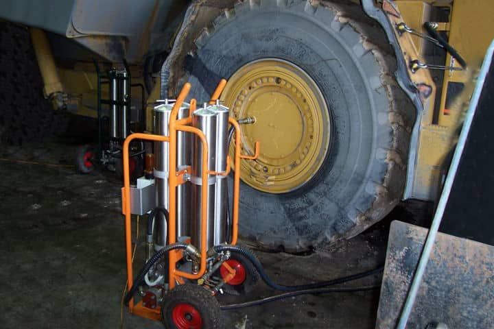 A tractor is sitting in a garage with a cart attached to it.