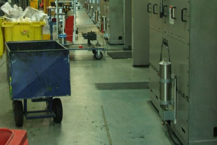 A blue cart is pulled by a yellow bin in a warehouse