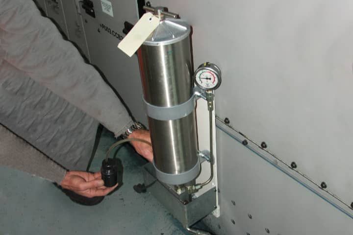 A person is standing next to a stainless steel container with a tag on it.