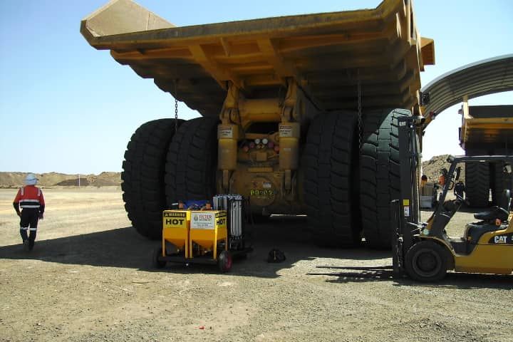 A large yellow dump truck is being lifted by a forklift