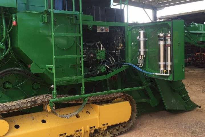 A green and yellow tractor is parked in a garage.