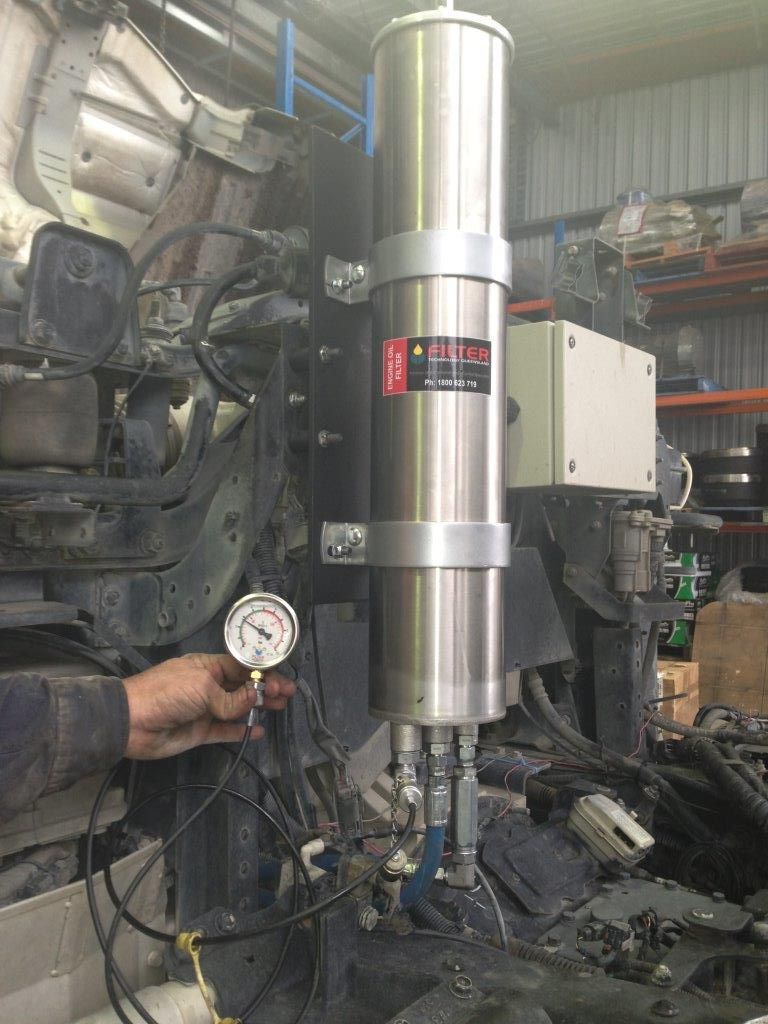 A man is holding a pressure gauge in front of a machine.