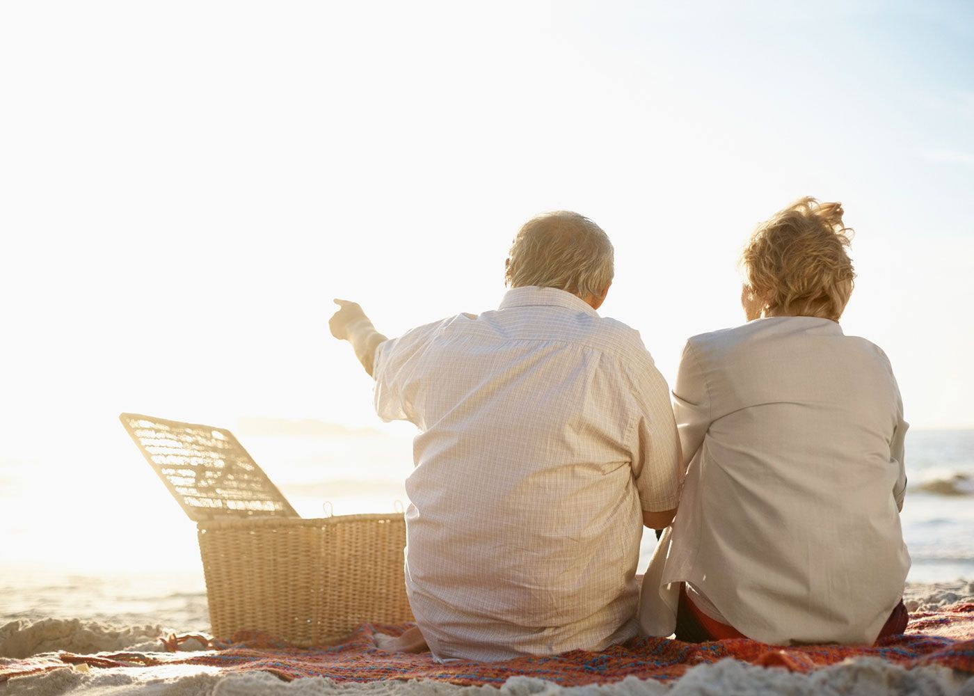 Retired couple sitting on the beach with their backs facing the camera