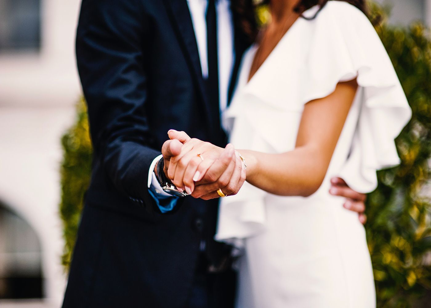 Couple holding hands with wedding rings on 