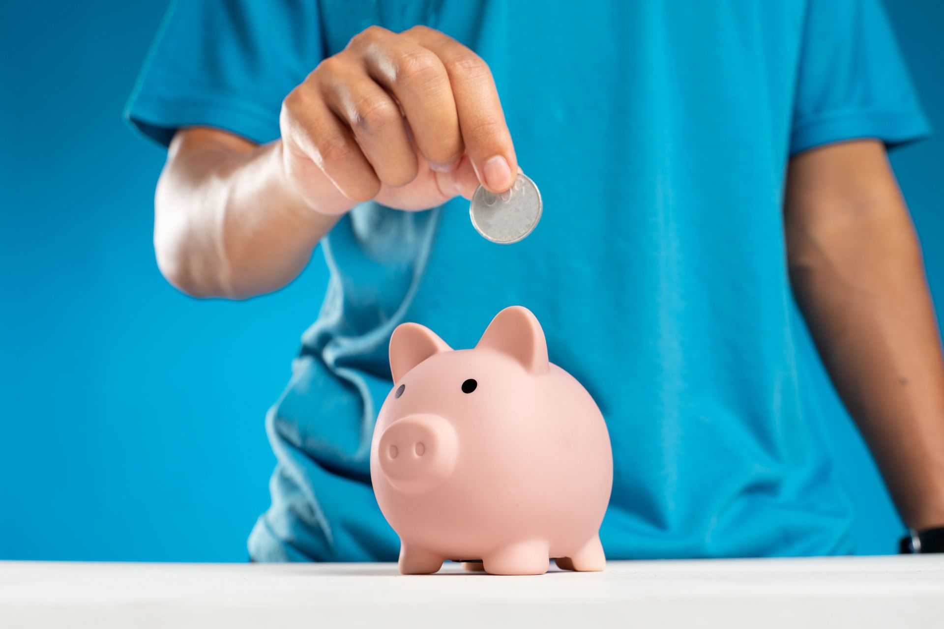 Child placing coins into a piggy bank while learning about saving and financial responsibility.