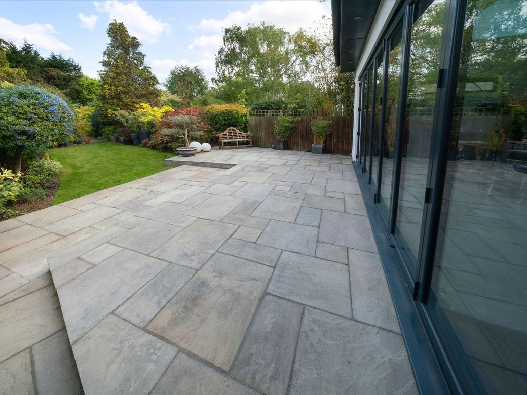 A large patio with sliding glass doors in a backyard.