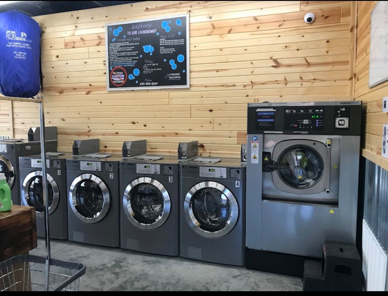 A row of washing machines in a laundromat with wooden walls.