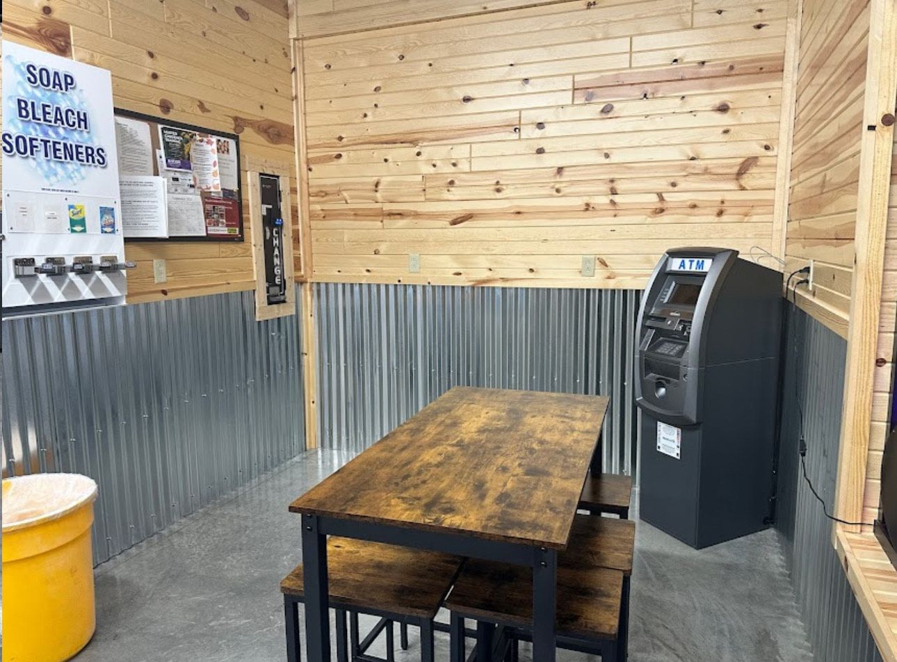 A room with a table and benches and a atm machine.